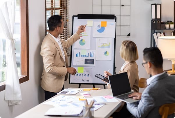A trainer presenting charts on a flip chart to colleagues in an office